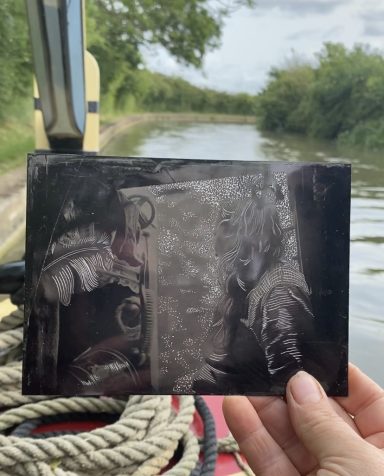 A tin type black and white photograph of a woman in the hatches of a narrowboat. The plate has been engraves with wood engraving tools.